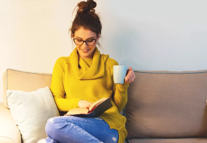 Une femme s’accorde une pause avec un livre et une tasse de thé.