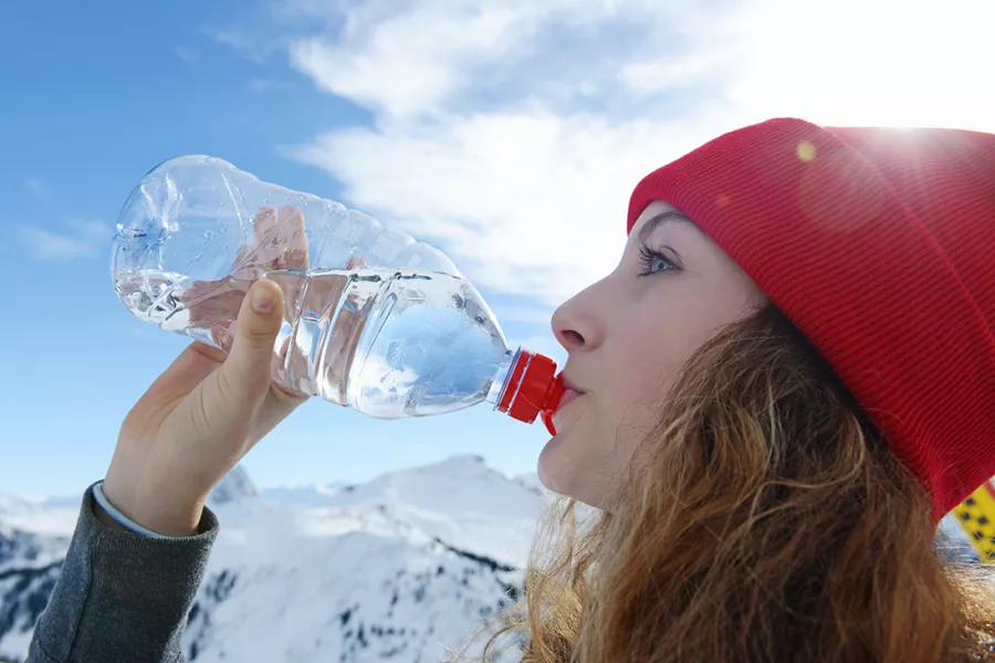 Une femme fait une pause dans sa journée de ski pour s’hydrater.