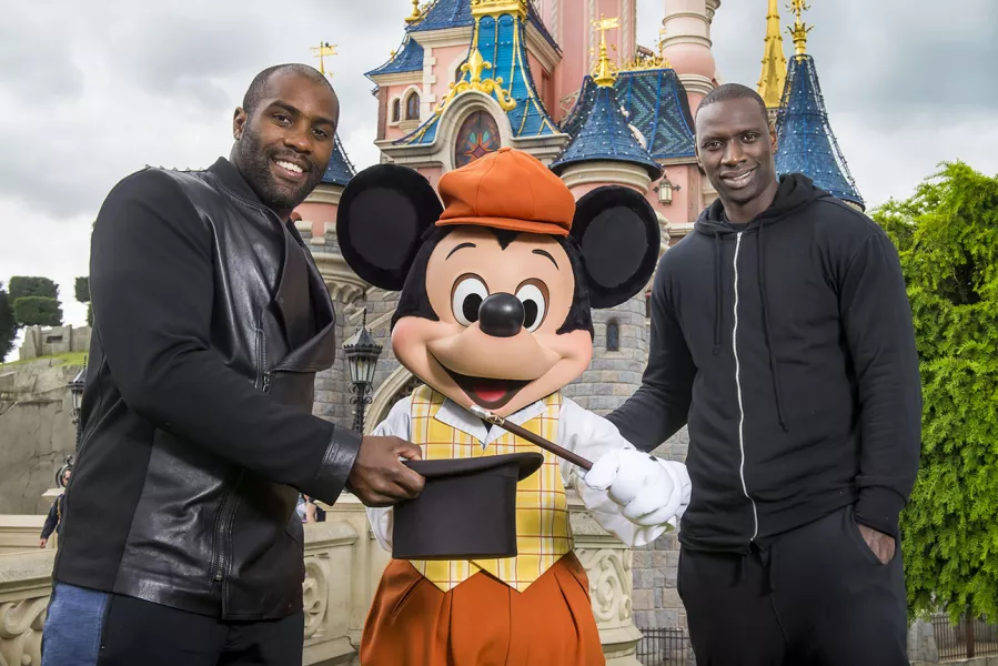 Rencontre au sommet devant le château de la Belle au Bois Dormant entre Teddy Riner, Omar Sy et Mickey.