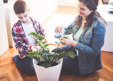 Une mère et son fils entretiennent une plante.
