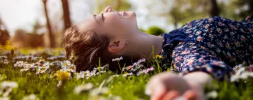 Une femme est allongée dans l’herbe dans un parc.