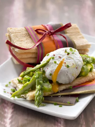 Cracotte® aux asperges vertes et œuf poché, herbes et baies roses