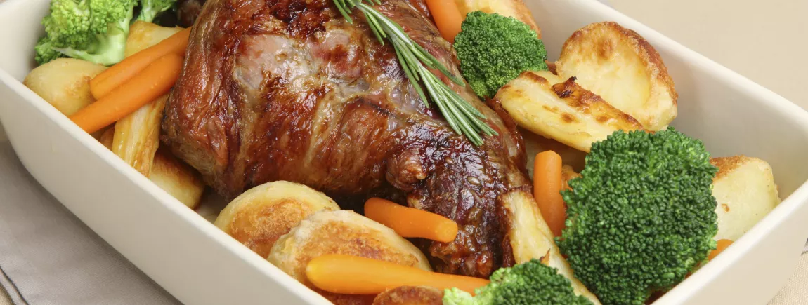 Gigot d’agneau servi à table dans son plat et ses légumes